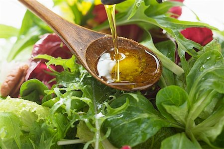 Pouring olive oil into wooden spoon above salad leaves Stock Photo - Premium Royalty-Free, Code: 659-01847400