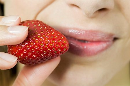 simsearch:659-01855246,k - Young woman holding fresh strawberry in front of her mouth Foto de stock - Sin royalties Premium, Código: 659-01847490