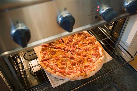 Warming up pepperoni pizza in oven Stock Photo - Premium Royalty-Free, Code: 659-01847593