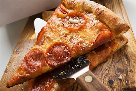 simsearch:659-03529071,k - Two pieces of pepperoni pizza with server on wooden board Foto de stock - Sin royalties Premium, Código: 659-01847616