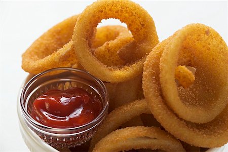 Deep-fried onion rings in white bowl, ketchup Stock Photo - Premium Royalty-Free, Code: 659-01847904