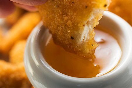 dipping sauce - Tremper une pépite de poulet en sauce aux abricots Photographie de stock - Premium Libres de Droits, Code: 659-01847938