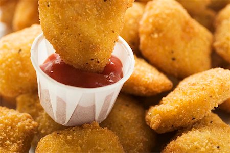 Dipping a chicken nugget in ketchup Stock Photo - Premium Royalty-Free, Code: 659-01847943