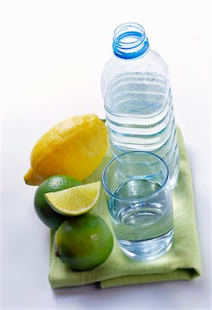 simsearch:659-01855169,k - Eau plate en bouteille et le verre à côté de citrons et citrons verts Photographie de stock - Premium Libres de Droits, Code: 659-01848361