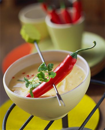 Chili pepper on fondue stick above cheese and chili sauce Stock Photo - Premium Royalty-Free, Code: 659-01848489