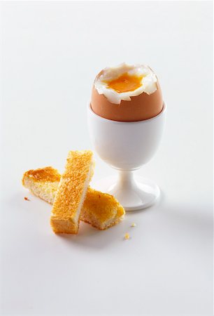 Breakfast egg in egg cup with top removed, pieces of toast Foto de stock - Sin royalties Premium, Código: 659-01848500