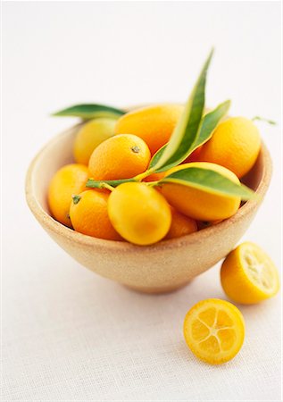 Kumquats in a bowl with two halves beside it Stock Photo - Premium Royalty-Free, Code: 659-01849026