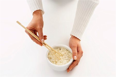 simsearch:659-08419252,k - Woman’s hands holding chopsticks in a bowl of rice (1) Fotografie stock - Premium Royalty-Free, Codice: 659-01849060