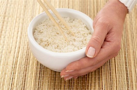simsearch:659-08419252,k - Woman’s hand holding a bowl of rice firmly on a bast cover Fotografie stock - Premium Royalty-Free, Codice: 659-01849061
