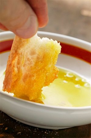 dunking food - Hand dipping a piece of white bread into a bowl of olive oil Stock Photo - Premium Royalty-Free, Code: 659-01849128