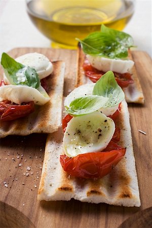 simsearch:659-01851287,k - Tomatoes and mozzarella on grilled bread, olive oil behind Stock Photo - Premium Royalty-Free, Code: 659-01849850