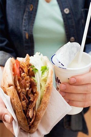 Hands holding a döner kebab and drinking yoghurt Stock Photo - Premium Royalty-Free, Code: 659-01842889