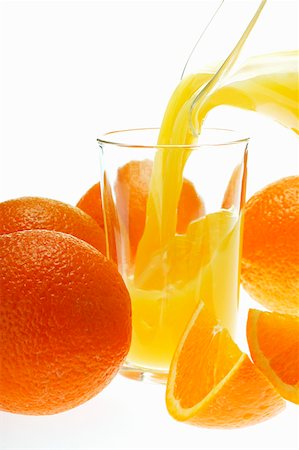 simsearch:659-03529641,k - Verser le jus d'orange en verre parmi les oranges Photographie de stock - Premium Libres de Droits, Code: 659-01843066