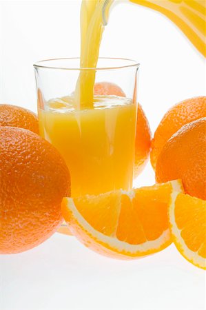 Pouring orange juice, oranges and orange wedges Stock Photo - Premium Royalty-Free, Code: 659-01843063