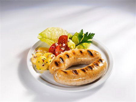 Zwei gegrillte Würstchen mit Kartoffeln und Tomaten-Salat Stockbilder - Premium RF Lizenzfrei, Bildnummer: 659-01854391