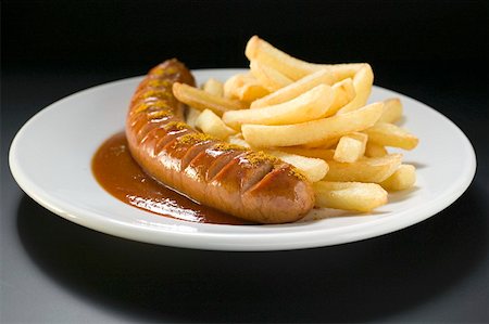 Currywurst with ketchup, curry powder and chips on a plate Stock Photo - Premium Royalty-Free, Code: 659-01854810