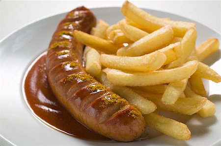 fried sausage recipe - Currywurst with ketchup, curry powder and chips on a plate Stock Photo - Premium Royalty-Free, Code: 659-01854813