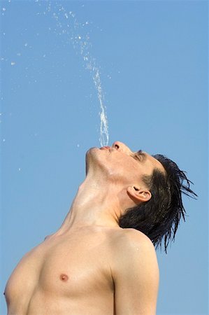 Man squirting water out of his mouth Stock Photo - Premium Royalty-Free, Code: 659-01855140