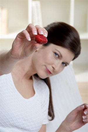 simsearch:659-01866601,k - Woman holding a strawberry towards the camera Foto de stock - Royalty Free Premium, Número: 659-01855205