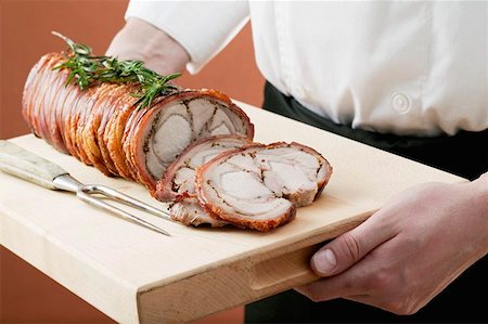 Rolled saddle of suckling pig on a wooden board Stock Photo - Premium Royalty-Free, Code: 659-01855387