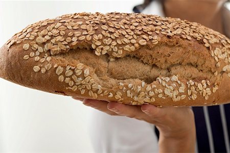 simsearch:659-01866634,k - Woman holding a loaf of oat bread on the flat of her hand Foto de stock - Sin royalties Premium, Código: 659-01856666