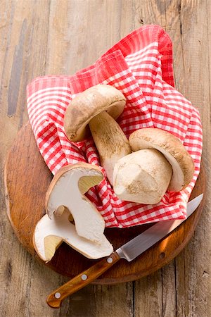 Three ceps, one halved, on wooden board with cloth Stock Photo - Premium Royalty-Free, Code: 659-01857259