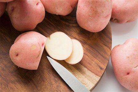 simsearch:659-06185085,k - Red potatoes, one partly sliced, on wooden board Stock Photo - Premium Royalty-Free, Code: 659-01857375