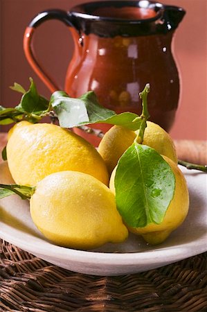 simsearch:659-01857464,k - Fresh lemons with leaves on plate in front of terracotta jug Stock Photo - Premium Royalty-Free, Code: 659-01857469