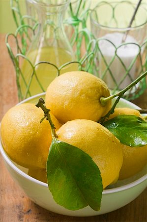 simsearch:659-01857464,k - Fresh lemons with leaves in bowl, lemon juice, sugar Stock Photo - Premium Royalty-Free, Code: 659-01857471