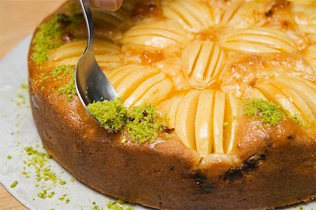 preparation of apple pie - Sprinkling apple cake with chopped pistachios Stock Photo - Premium Royalty-Free, Code: 659-01857596