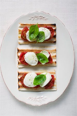 simsearch:659-01857570,k - Three tomato and mozzarella toasts with basil Foto de stock - Sin royalties Premium, Código: 659-01857994