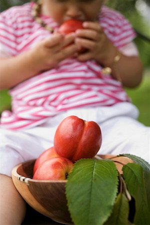 simsearch:659-01864546,k - Nectarines in wooden bowl, child eating nectarine in background Stock Photo - Premium Royalty-Free, Code: 659-01858229