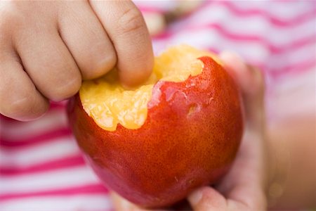 simsearch:659-01858229,k - Child holding nectarine with bites taken Fotografie stock - Premium Royalty-Free, Codice: 659-01858231