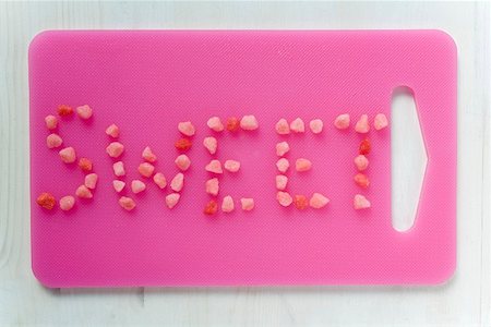 The word 'Sweet' written in sweets on pink chopping board Stock Photo - Premium Royalty-Free, Code: 659-01858743