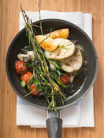 dicentrarchus labrax - Sea bass cutlets with vegetables, herbs, lemon in frying pan Foto de stock - Royalty Free Premium, Número: 659-01858952