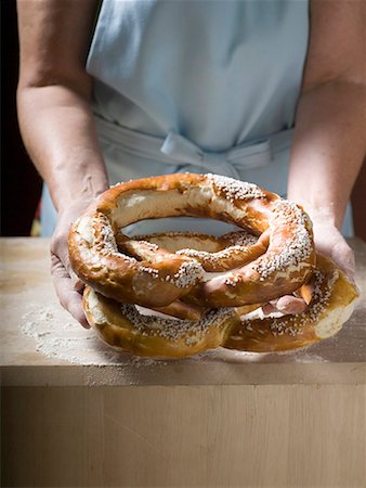 Woman holding two large soft pretzels Stock Photo - Premium Royalty-Free, Code: 659-01858974