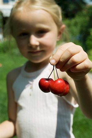 simsearch:659-01858229,k - Blond girl holding three cherries Fotografie stock - Premium Royalty-Free, Codice: 659-01859048