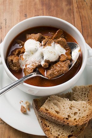 Goulash soup with sour cream in soup cup, slices of bread Stock Photo - Premium Royalty-Free, Code: 659-01859164