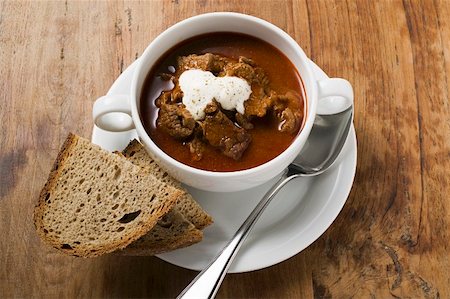 Goulash soup with sour cream in soup cup, slices of bread Stock Photo - Premium Royalty-Free, Code: 659-01859162