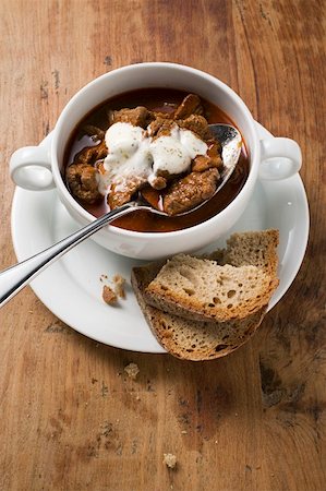 Goulash soup with sour cream in soup cup, slices of bread Stock Photo - Premium Royalty-Free, Code: 659-01859163