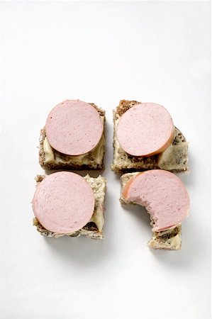 simsearch:659-01848335,k - Four open sausage sandwiches with mustard, one with bite taken Foto de stock - Sin royalties Premium, Código: 659-01859172