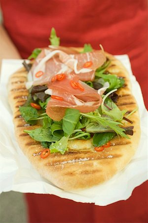 flat bread - Woman holding pizza bread topped with Parma ham, herbs, chilli rings Stock Photo - Premium Royalty-Free, Code: 659-01859217