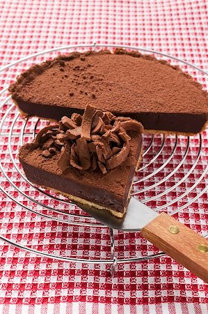 Chocolate tart on cake rack and piece on cake server Stock Photo - Premium Royalty-Free, Code: 659-01859307