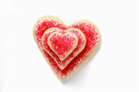 Heart-shaped biscuits with red sugar, in a pile Stock Photo - Premium Royalty-Free, Code: 659-01859564