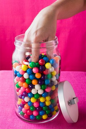 Hand reaching into jar of coloured bubble gum balls Fotografie stock - Premium Royalty-Free, Codice: 659-01859639