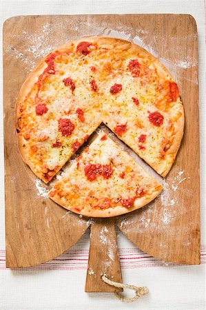 simsearch:659-01859989,k - Pizza Margherita, a slice cut, on chopping board Foto de stock - Sin royalties Premium, Código: 659-01859926