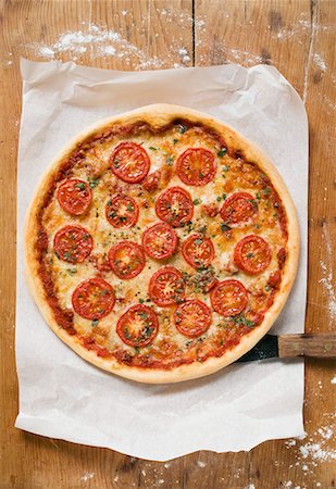 pizza top view - Cheese and tomato pizza with oregano on paper Stock Photo - Premium Royalty-Free, Code: 659-01859957