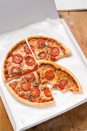 Cheese & tomato pizza with oregano (quartered) in pizza box Stock Photo - Premium Royalty-Free, Code: 659-01859963