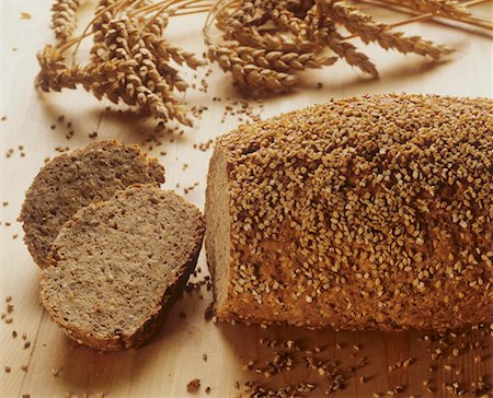 pane integrale - Wholemeal wheat bread with sesame crust, ears of wheat behind Fotografie stock - Premium Royalty-Free, Codice: 659-01851144