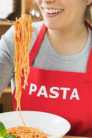 simsearch:659-01855701,k - Young woman in apron eating spaghetti with tomato sauce Stock Photo - Premium Royalty-Free, Code: 659-01851200